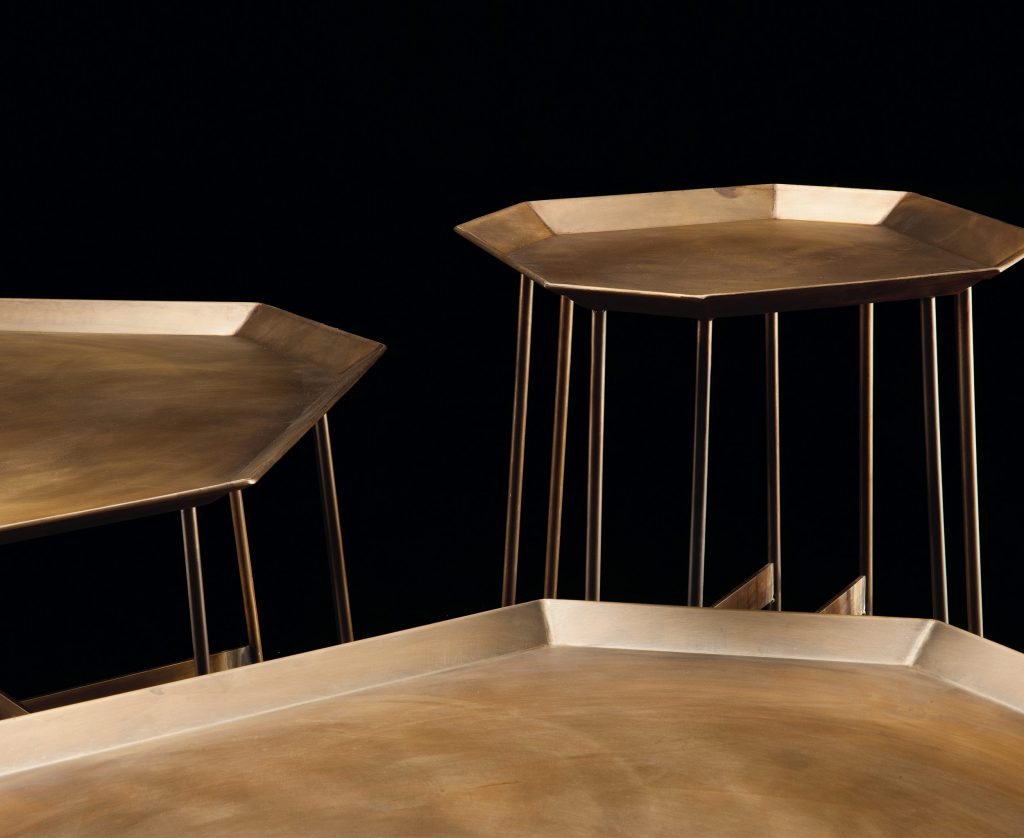Three Octagon Tables, finish structure and eight legs in burnished brass, tabletops in brass on a black background.