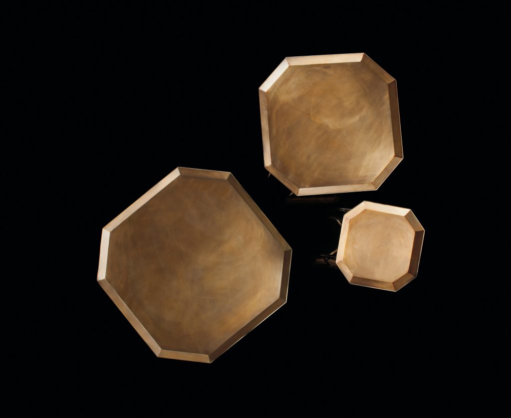 Three Octagon Tables, finish structure and eight legs in burnished brass, tabletops in brass on a black background.