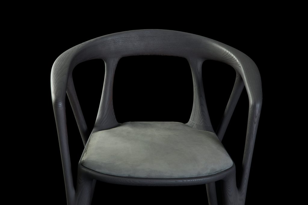 Savanna dining chair in black wood with four legs. Seat covered with black leather on a black background.