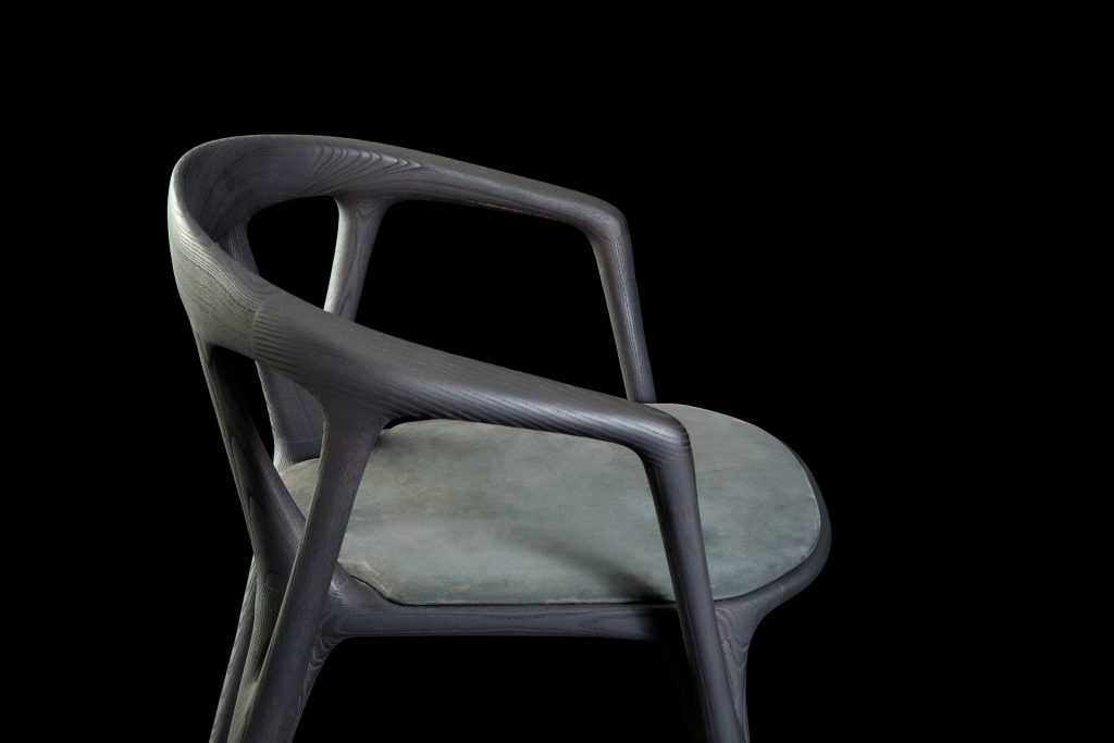 Savanna dining chair in black wood with four legs. Seat covered with black leather on a black background.