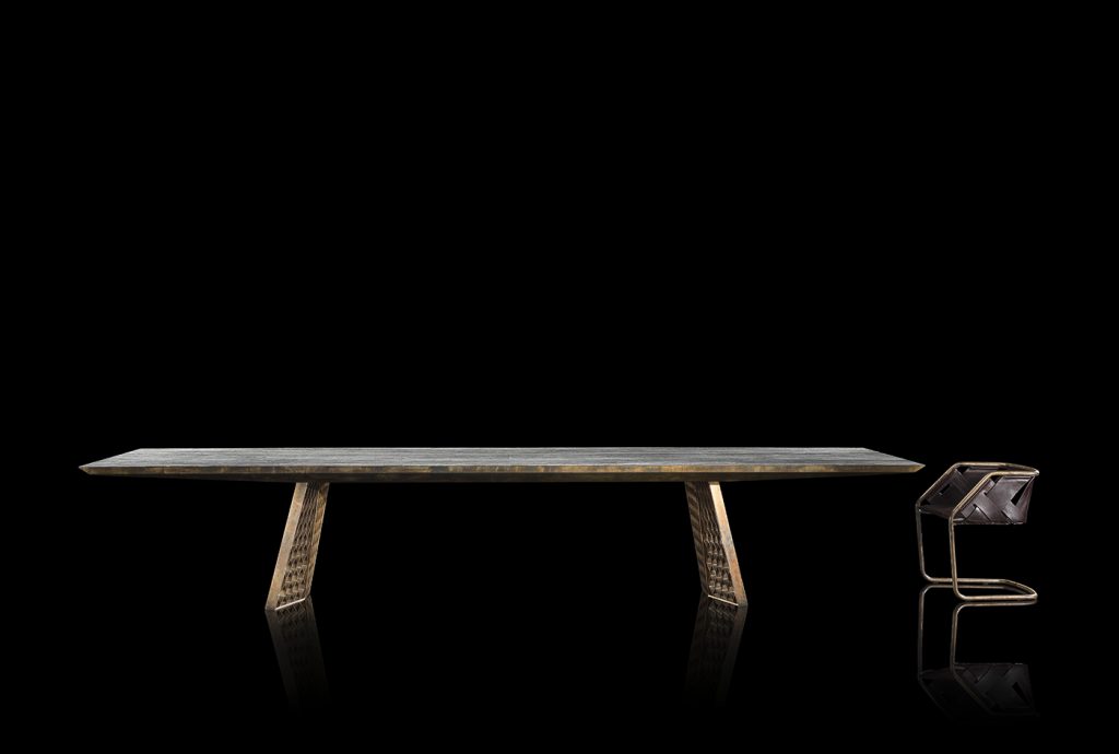 Stealth Table, legs in brass finish with rhombus pattern, top in gray grained wood stone on a black background.