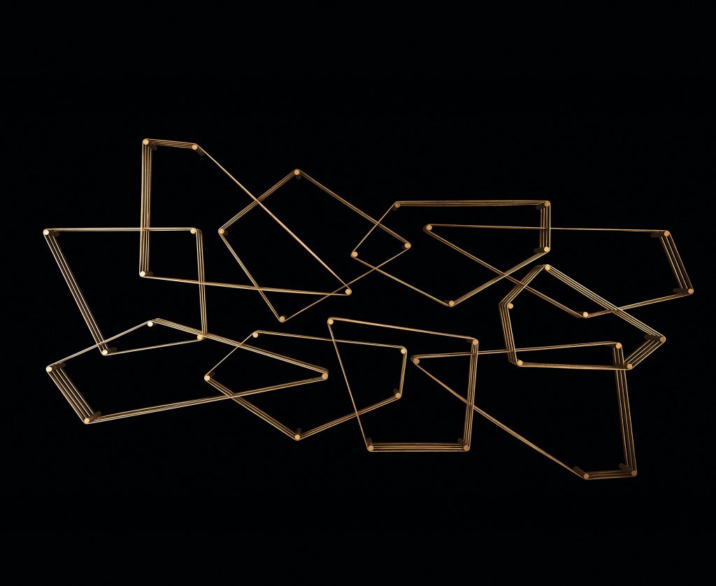 Tangram bookcase made of irregular polygons joined together. Structure in natural burnished brass attached to a black wall.