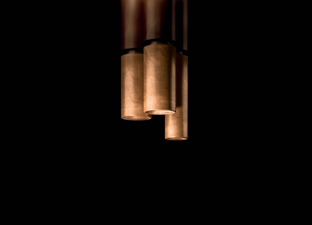 Three cylindrical ceiling Tele Lights made of burnished brass and silver on a black background.