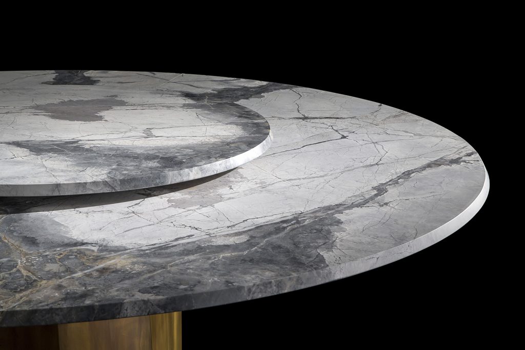 Zenith Table , white and black marble top, central leg in gold brass casing on a black background.