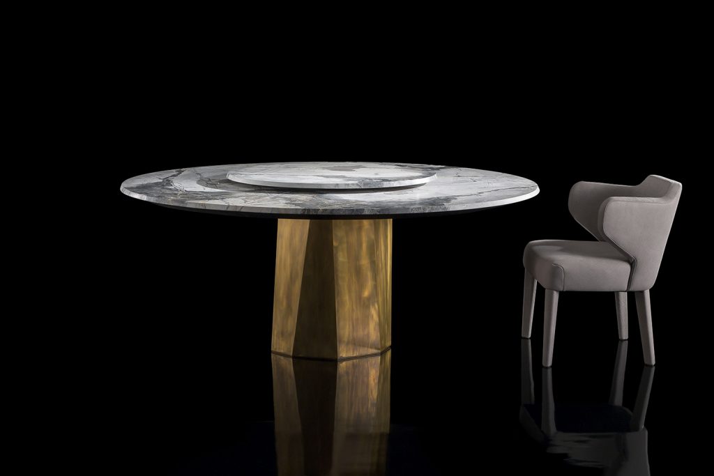 Zenith Table , white and black marble top, central leg in gold brass casing on a black background.