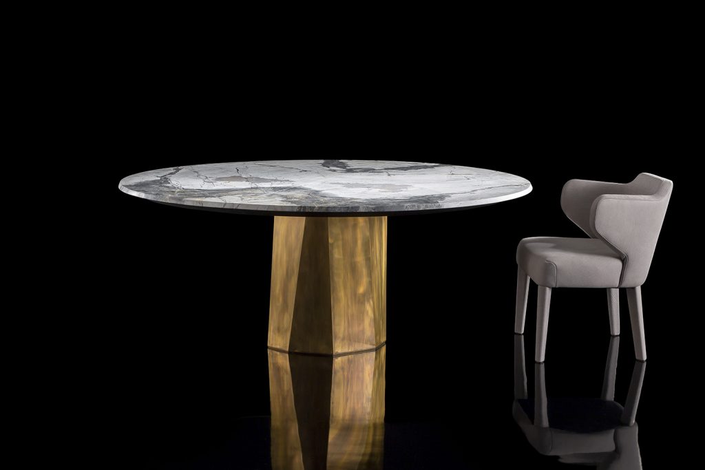 Zenith Table , white and black marble top, central leg in gold brass casing on a black background.