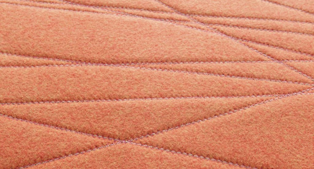 Flussi rug made of orange felt and embriodered in a rectangle.