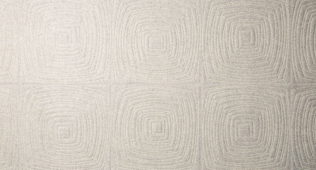 Imperfetto of beige square felt. The embroidery on each element creates an irregular squared spiral-like pattern.