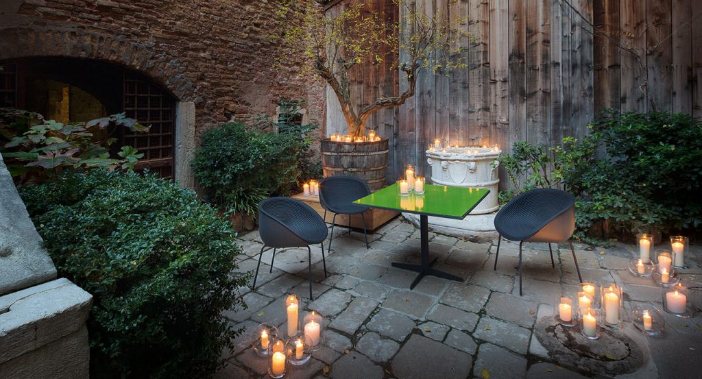Three black Amable Outdoor Chairs, four legs of black steel, molded polyethylene shell and rope cord cover in a terrace.