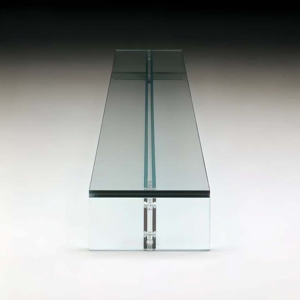 A modern glass table with a sleek, transparent design, featuring a thick glass top supported by a central glass beam and base, set against a gradient backdrop