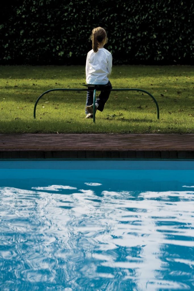 Allunaggio stool with a round green seat and metal legs in the countryside.