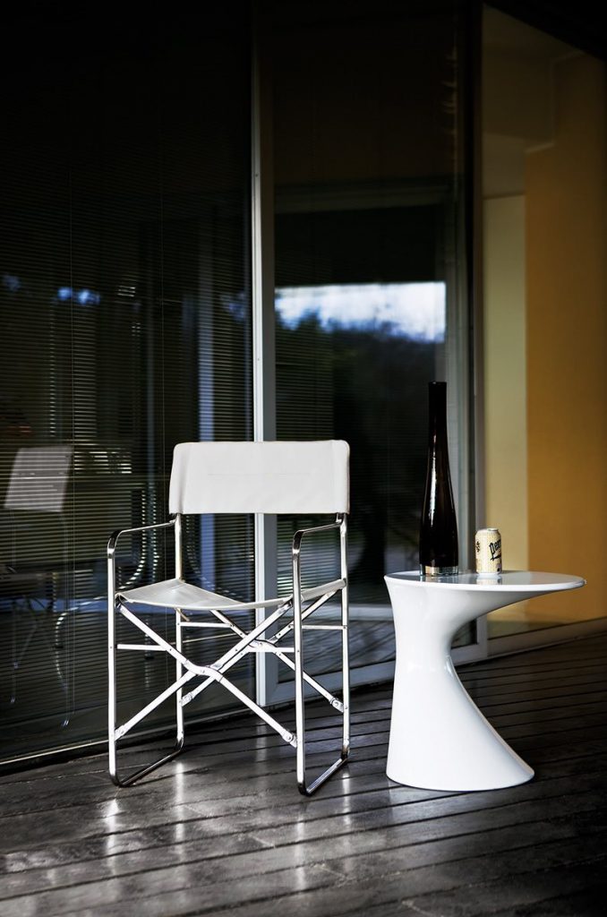 Folding chair. Back and seat in white leather. Silver metal structure on a terrace.