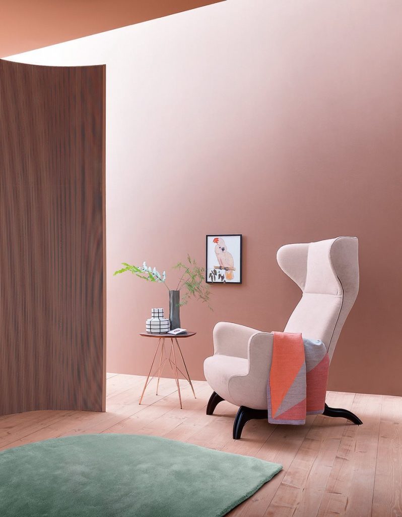 Ardea armchair with a white fabric upholstery and black wooden legs in a living room.