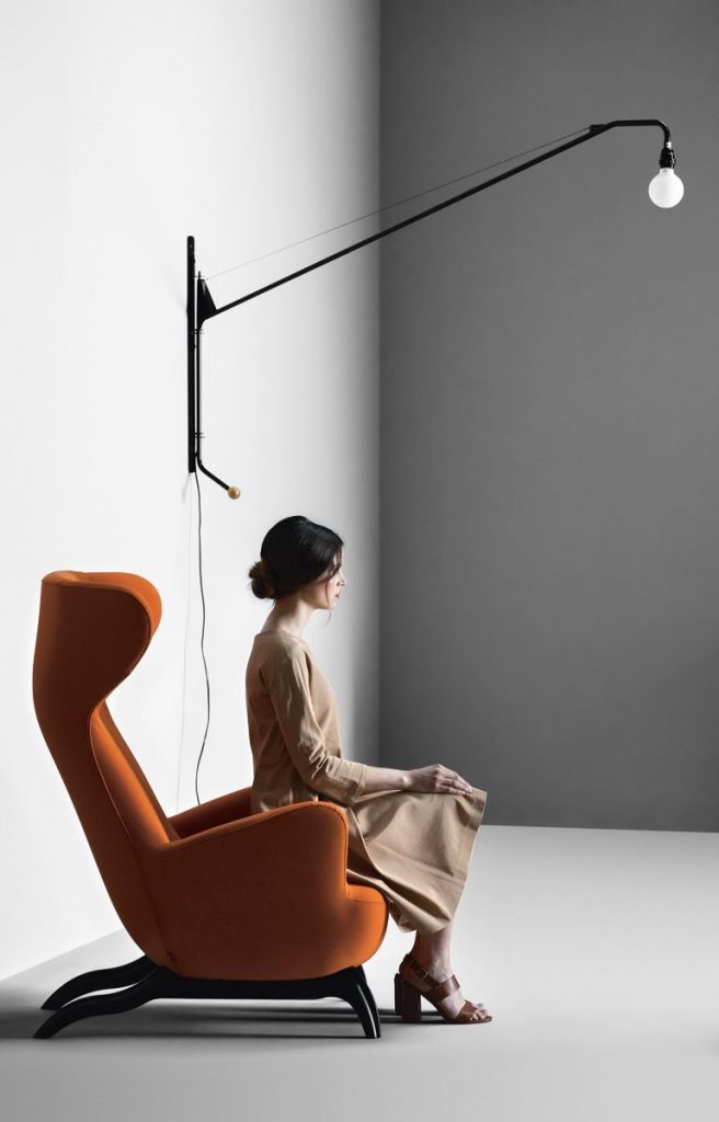 Ardea armchair with a orange fabric upholstery and black wooden legs in a living room.