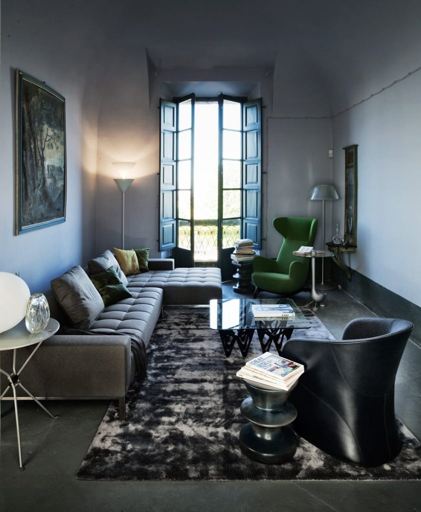 Ardea armchair with a green fabric upholstery and black wooden legs in a living room.