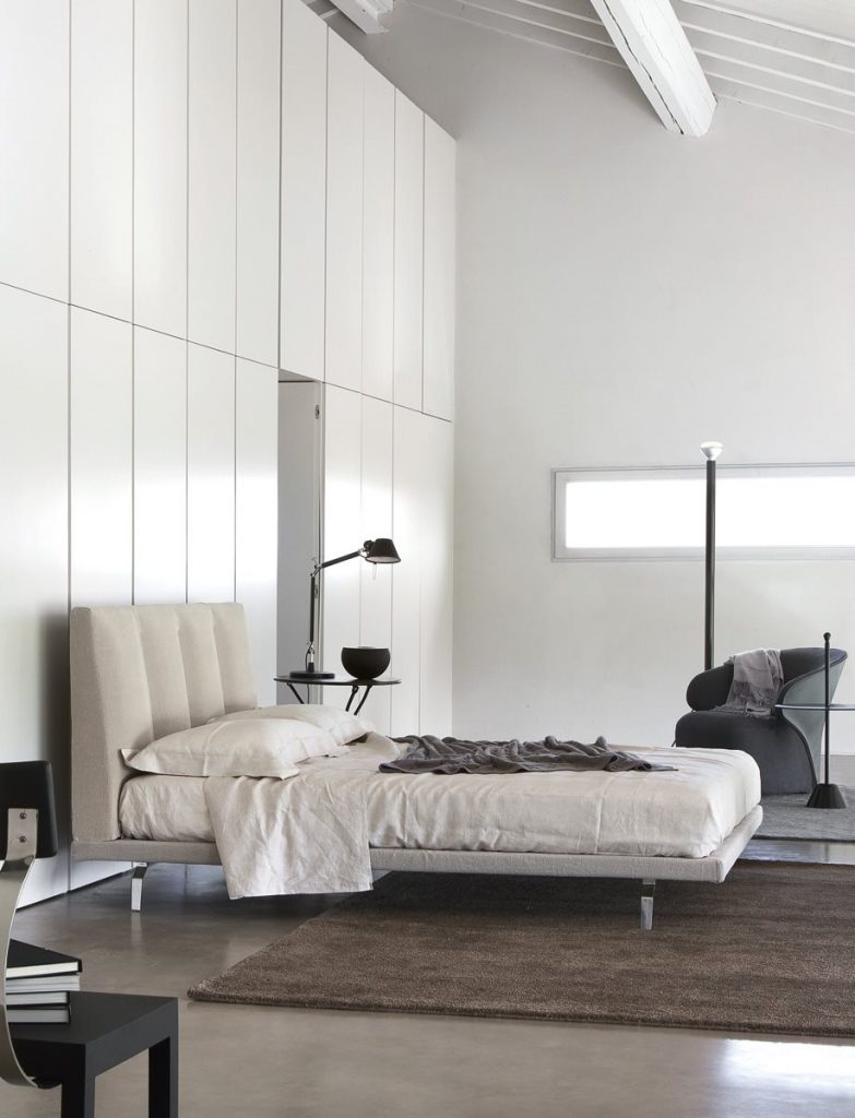 Arom armchair upholstered in two shades of gray fabric in a bedroom.