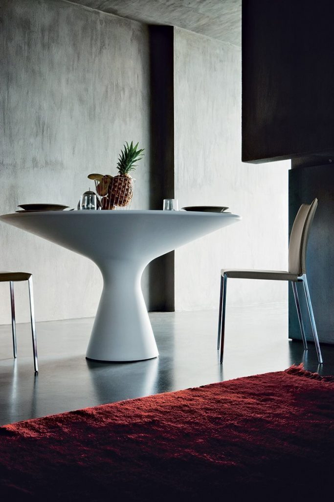Blanco table with a round white top and wooden legs in a room in a dining room.