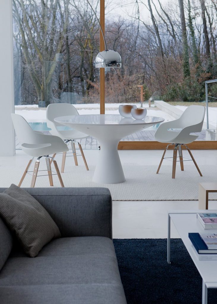 Blanco table with a round white top and wooden legs in a room in a dining room.