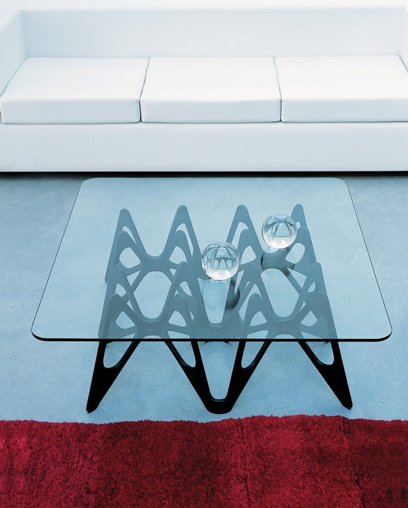 Butterfly coffee table. Top in transparent glass and base en black with butterfly like pattern in a living room.