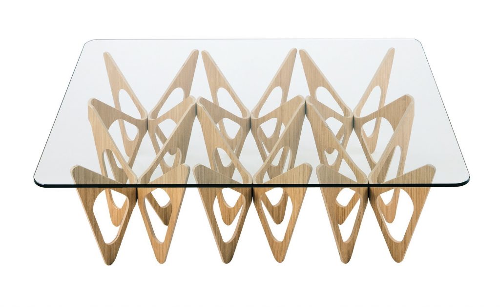 Butterfly coffee table. Top in transparent glass and base in gold with butterfly like pattern on a white background.