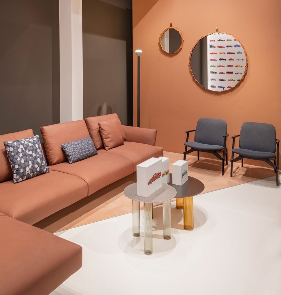Two Echino coffee table. Round gray top and three semi transparent cilindrical legs, one in bronze and one in gray in a living room.