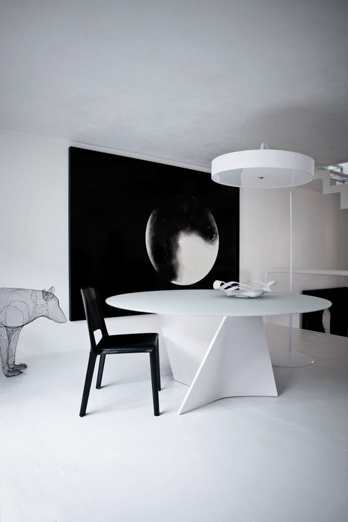 Elica table, white top and central spiral like leg in white in a dining room.