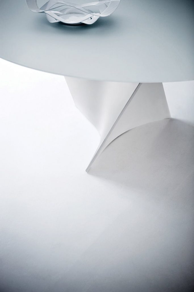 Closeup of Elica table, white top and central spiral like leg in white on a white background.