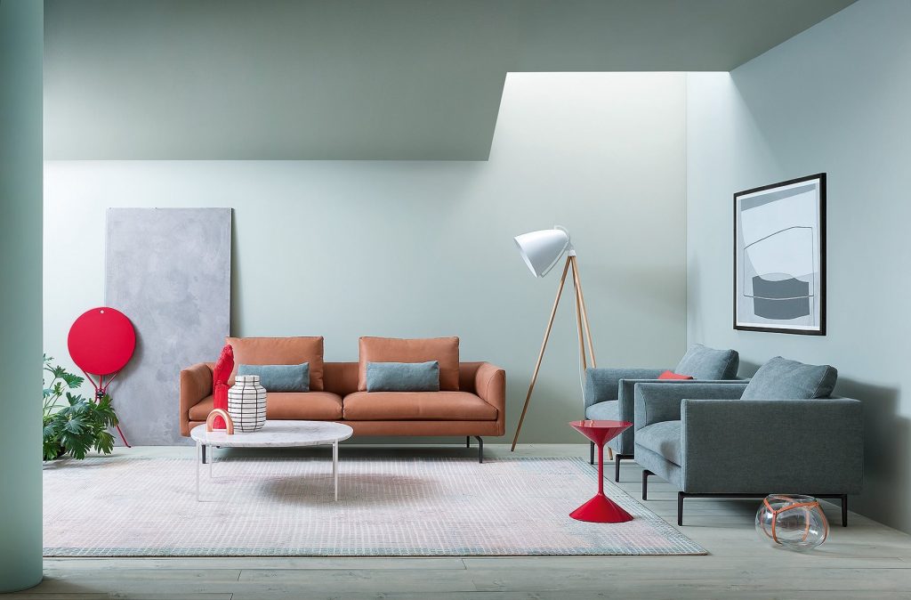 Flamingo sofa upholstered in red fabric with silver steel legs in a living room.