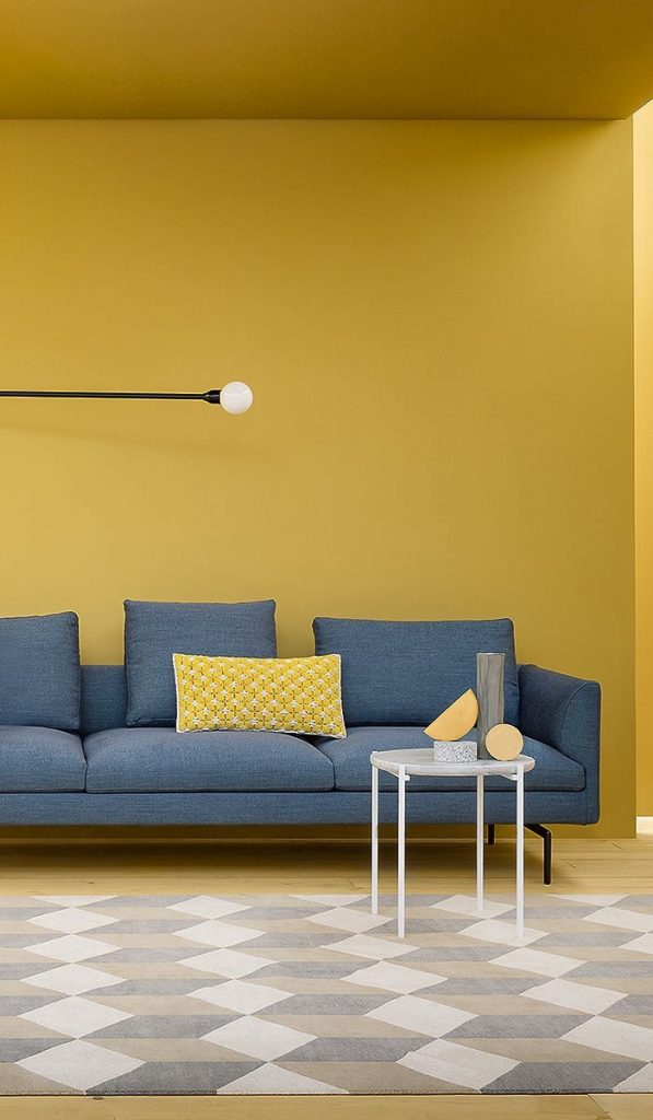 L shaped Flamingo sofa upholstered in blue fabric with silver steel legs in a living room.