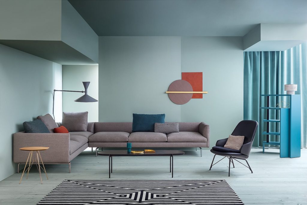 L shaped Flamingo sofa upholstered in purpure fabric with silver steel legs in a living room.