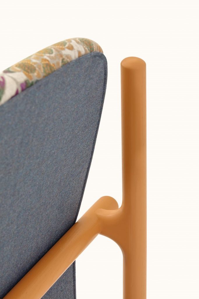 Closeup of Florin bed. Headboard with green and pink floral pattern, base and four legs in wood upholstered in gray fabric on a white background.