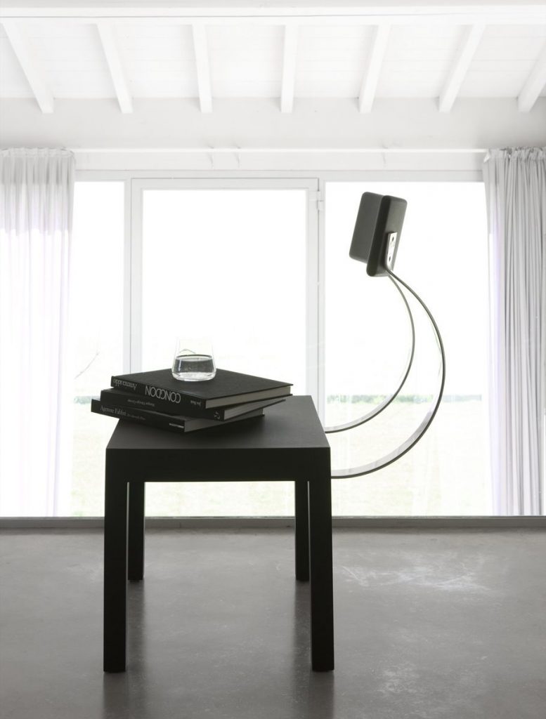 Follia chair with a unique design, featuring a silver metal frame. Backrest and structure with legs in black on a gray floor.