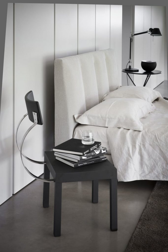 Follia chair with a unique design, featuring a silver metal frame. Backrest and structure with legs in black ina bedroom.