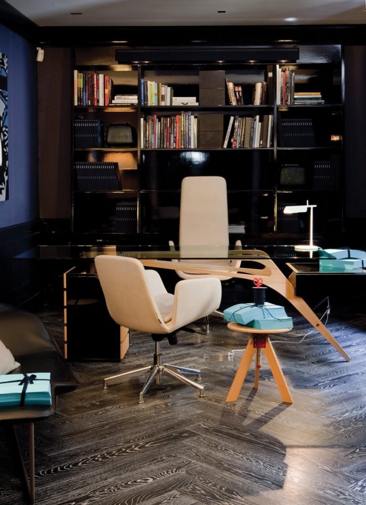 Giotto stool, round top and three legs in natural wood color in an office.