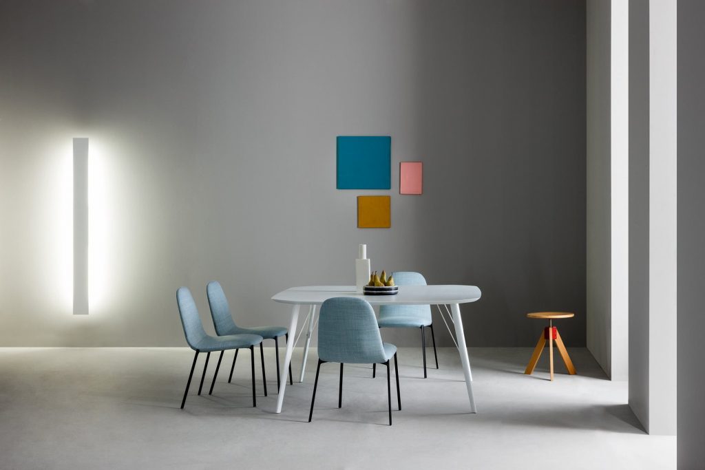 Giotto stool, round top and three legs in natural wood color in a dining room.