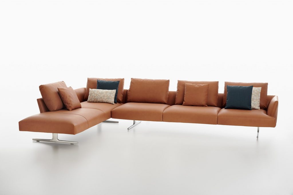 L shaped Hiro sifa with backrest and armrest in brown fabric and four black legs on a white background.