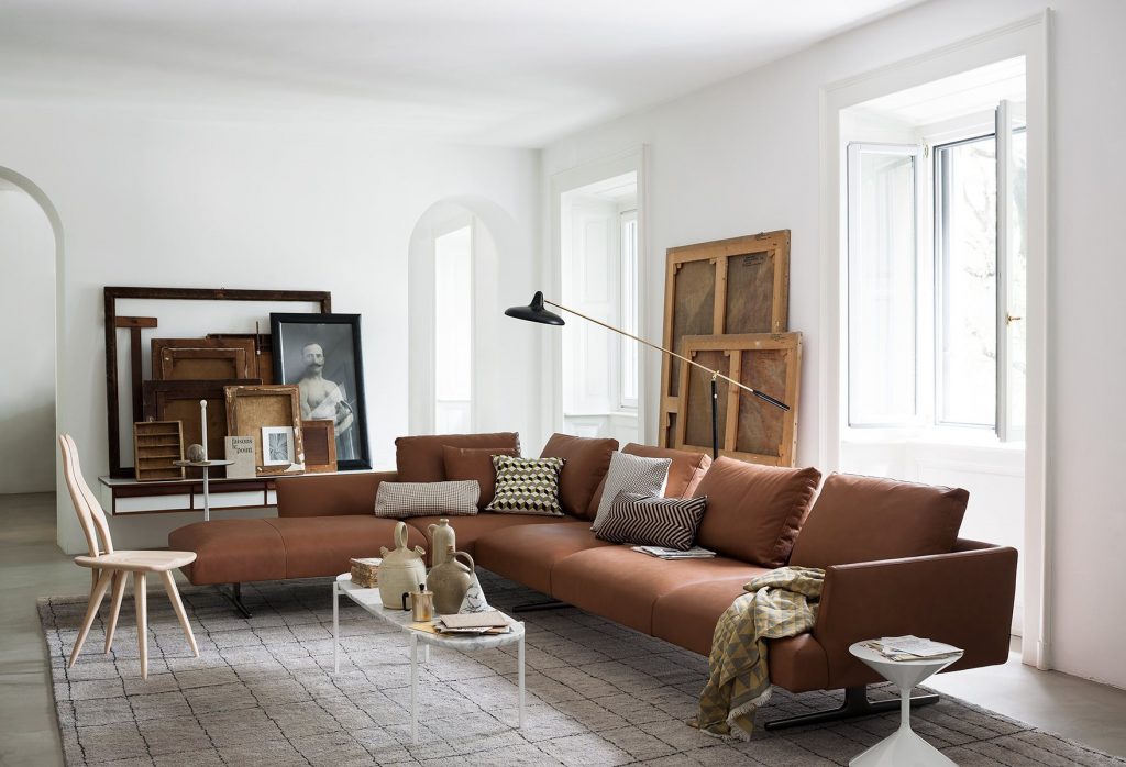 L shaped Hiro sifa with backrest and armrest in brown fabric and four black legs in a living room.