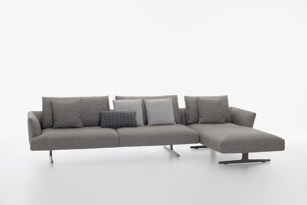 L shaped Hiro sifa with backrest and armrest in gray fabric and four black legs on a white background.