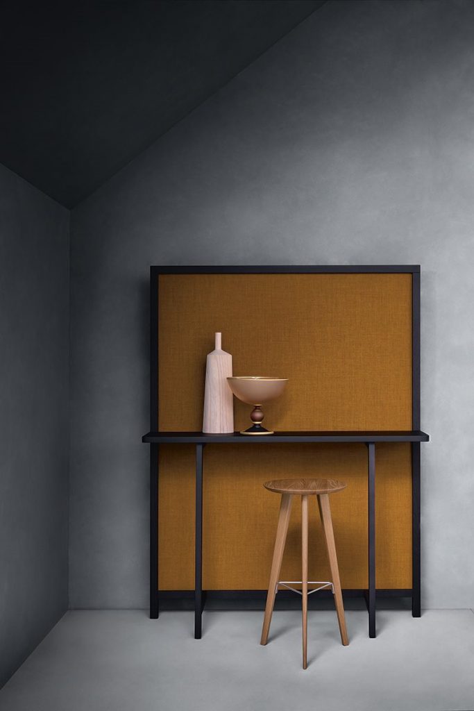 Ido chair made of wood with a round top and four legs united by metal rods under a table.