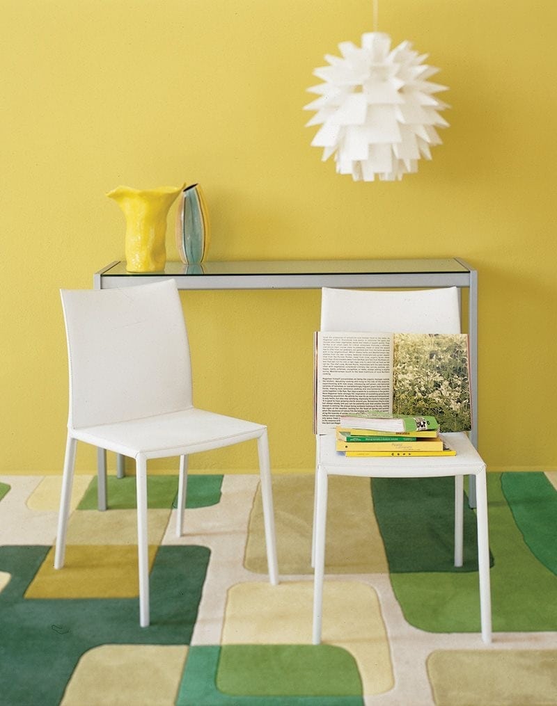Two Lea chairs featuring a high backrest and a upholstered seat and backrest in white fabric with four white legs in a office room.