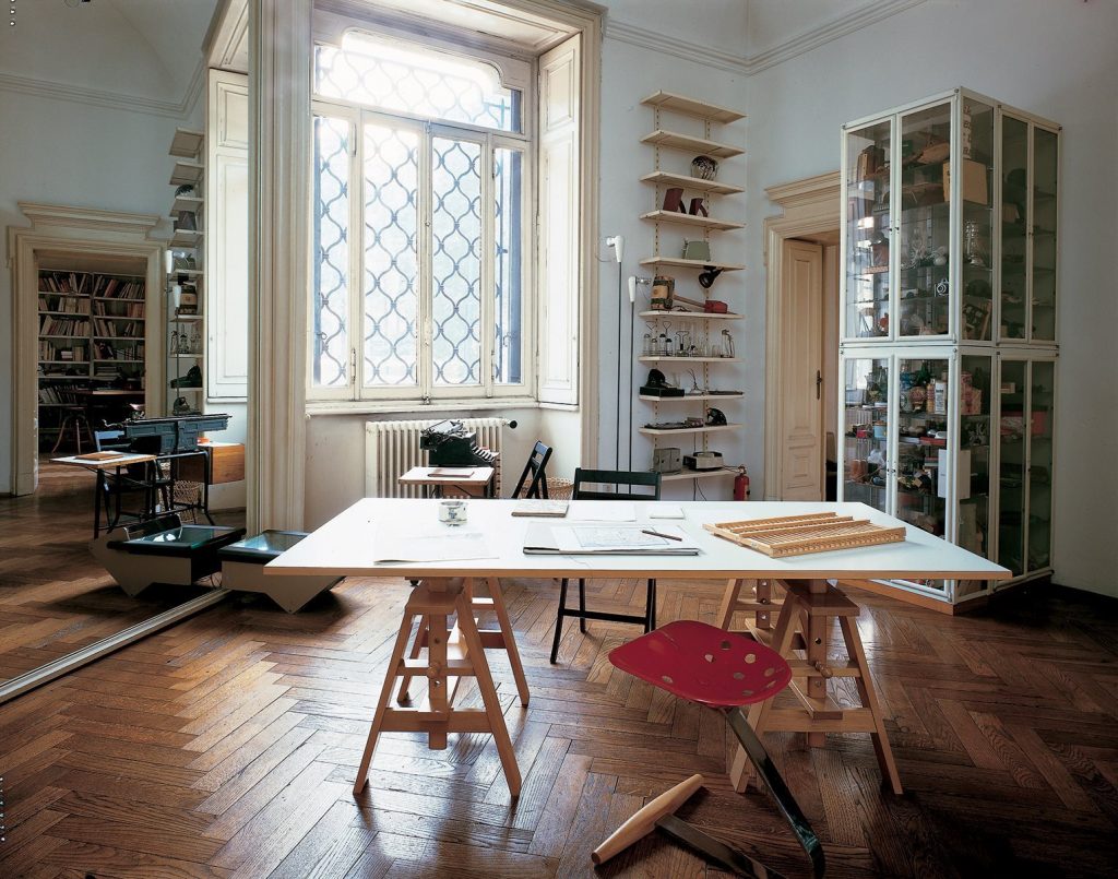 Square Leonardo table featuring a white wooden top and four wooden sturdy legs in a office.