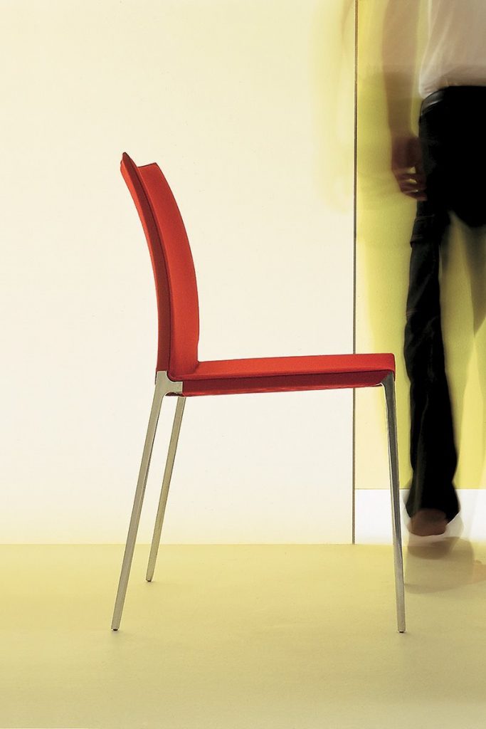 Lia chair featuring a silver metal frame and four legs. Red cushioned seat and backrest on a yellow background.