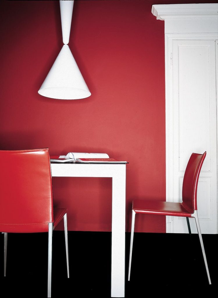 Two Lia chairs featuring a silver metal frame and four legs. Red cushioned seat and backrest in a dining room.
