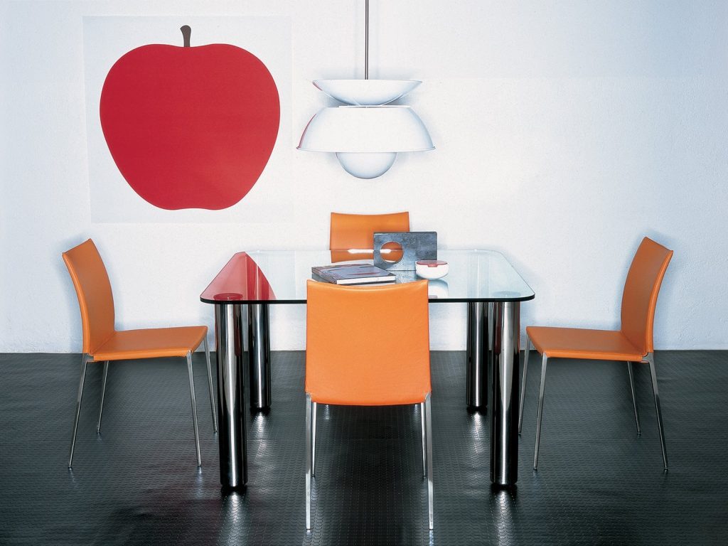 Marcuso table with a glass top and four black sturdy metal legs in a dining room.