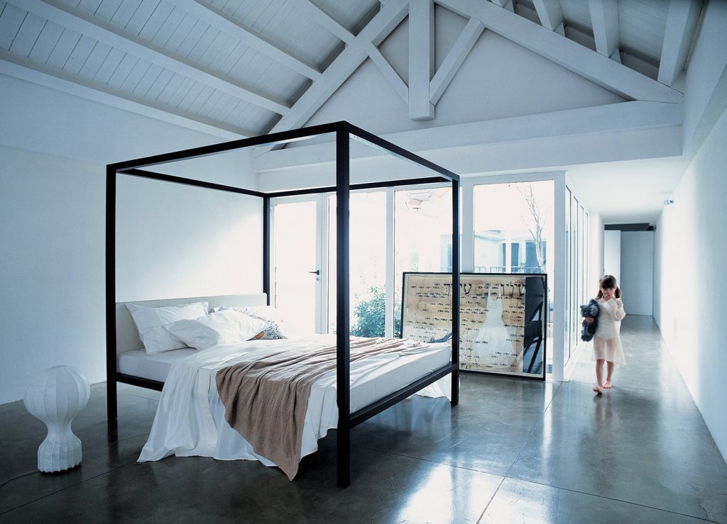 Milleunanotte bed with a classic, elegant design, featuring a high, tufted headboard and a black frame in a bedroom.