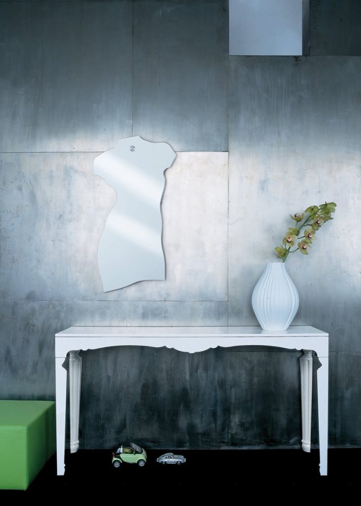 Milo mirror in the shape of the torso of the human body on a gray wall.