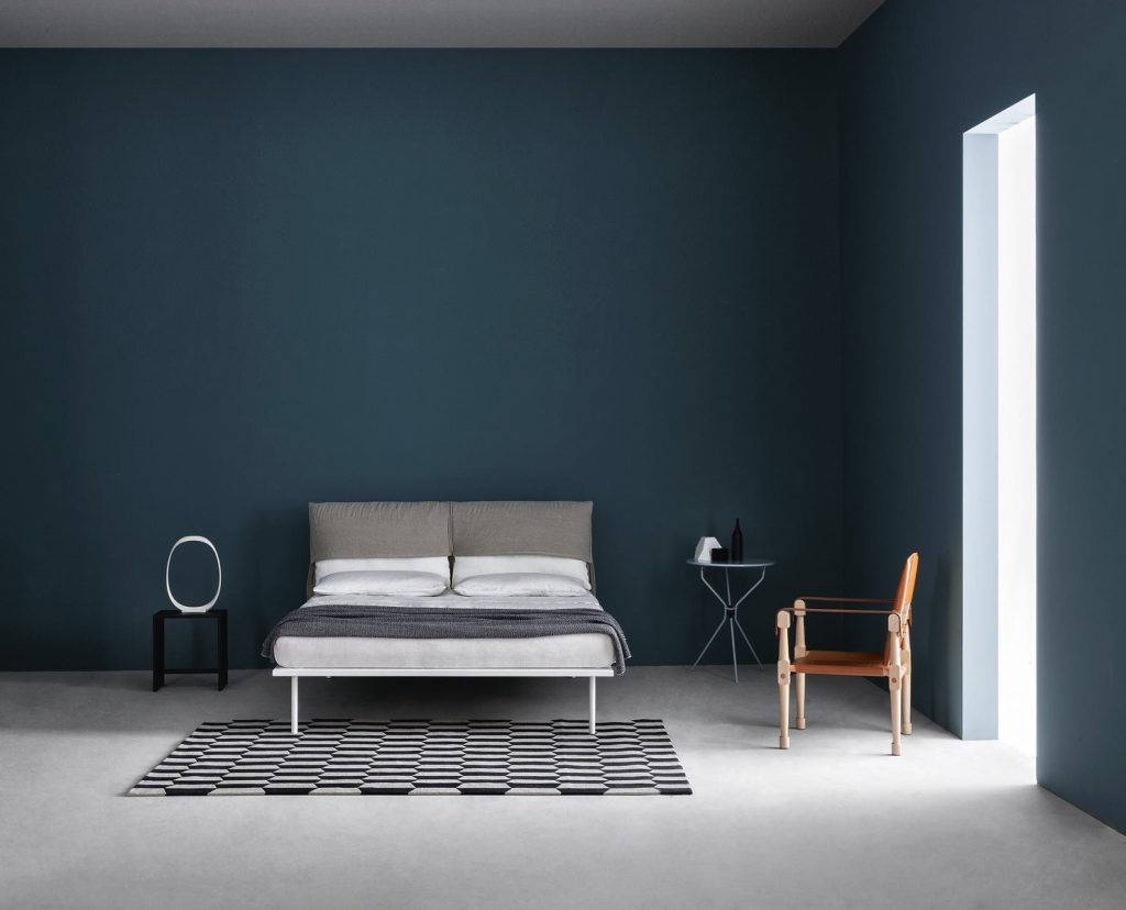 Moretta bench in natural wood, seat and backrest in brown fabric in a bedroom.