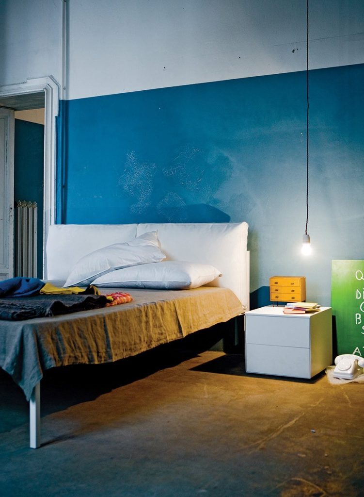 Nyx bed featuring a white padded headboard and white frame and four legs in a bedroom.