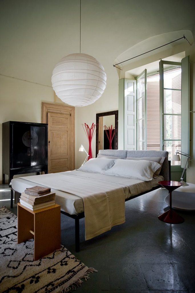 Nyx bed featuring a white padded headboard and white frame and four legs in a bedroom.