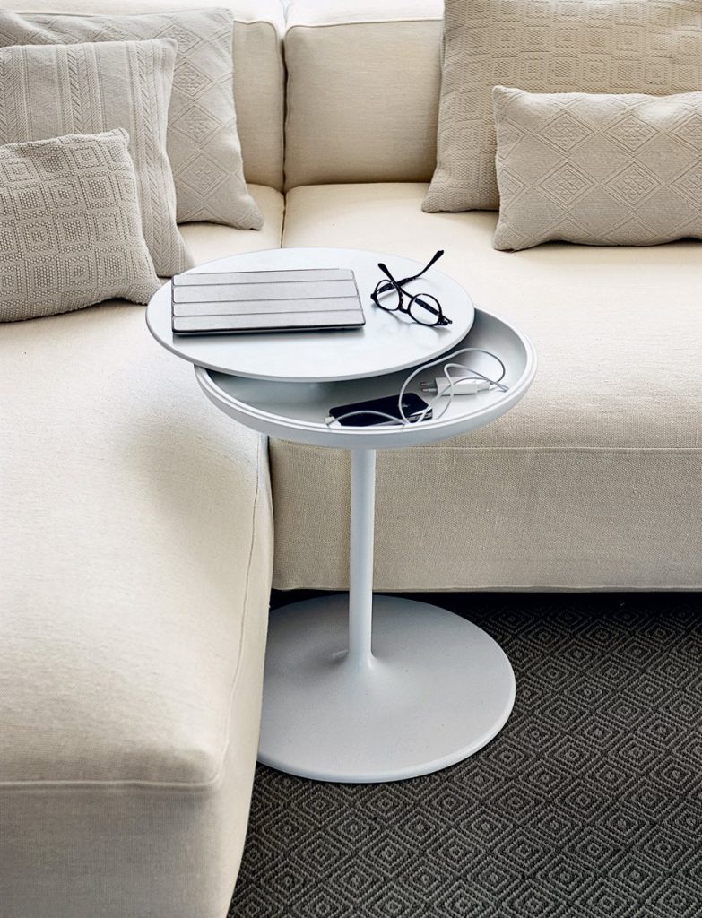 Toi side table with a round white top and central leg, in a living room.